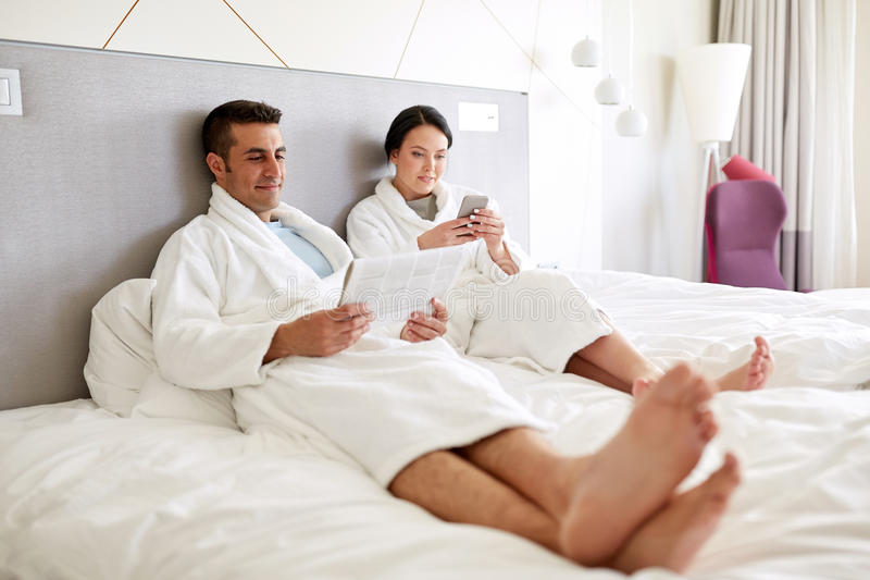 A married couple is resting on a bed in a hotel.
